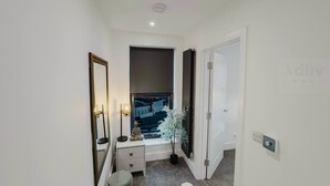 A narrow hallway with a window, a bedside table, a lamp, and a small potted plant. - Luxury Seaside Home Parking Sleeps 8 by Adliv (Margate)
