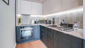 Una cucina moderna con mobili scuri, forno integrato, microonde e macchina del caffè.