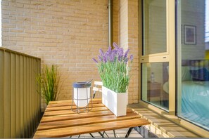 A wooden table with a white planter box containing green plants and a metal lantern. - Central London Stay in Vauxhall With Balcony (London)