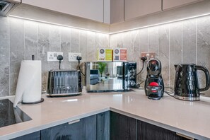 Una cocina moderna con tostadora, cafetera, hervidor y un soporte para toallas de papel.