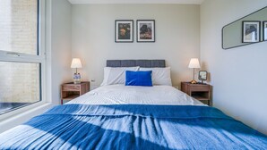 Una camera da letto con un letto, due comodini, una finestra e due quadri appesi al muro.