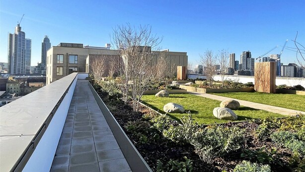A rooftop garden with a pathway, greenery, and a cityscape in the background. - Central London Stay in Vauxhall With Balcony (London)