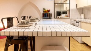 A modern kitchen with a tiled island, a microwave, a fruit bowl, and a washing machine.
