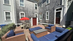 A patio area with wicker furniture and a red umbrella. - Entire Charming Victorian Home Downtown Newport (Newport)