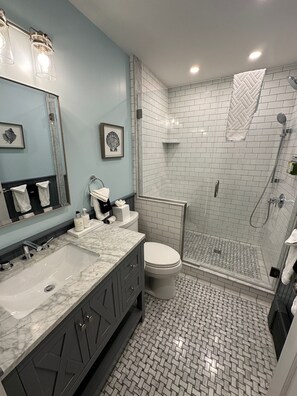 Een moderne badkamer met een grote spiegel, twee wastafels, een toilet en een ruime douche.