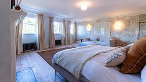 A bedroom with a large bed, a sofa, a radiator, and a window with curtains.