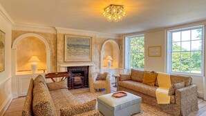 A room with two leopard-print sofas, a fireplace, and large windows with natural light.