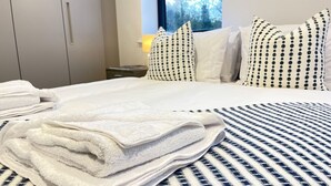 A neatly made bed with white towels, a striped bedspread, and polka-dotted pillows in a hotel room. - Luxury Ocean North Foreland Golf View By Adliv (Broadstairs)