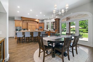 Una cocina amplia con armarios de madera, una isla central y una zona de comedor con una mesa redonda y sillas.