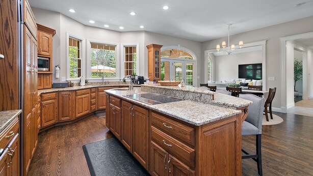 A spacious kitchen with wooden cabinets, a large island, and a dining area with a TV. - Private Riverbank 27-acre Estate 1 hr From Chicago (Kankakee)