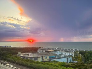 Une vue sur la côte, avec un coucher de soleil, des bâtiments et une route.