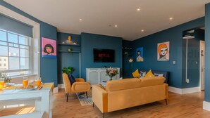 Een moderne woonkamer met een bank, een televisie en kunstwerken aan de muren.