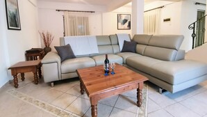 A living room with a sectional sofa, a wooden coffee table, and a small side table. - Sobella Villa - 3 Bedroom Villa With 10 x 4 Pool (Paralimni)