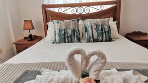 A neatly made bed with a heart-shaped towel arrangement, a decorative pillow, and a rose. - Sobella Villa - 3 Bedroom Villa With 10 x 4 Pool (Paralimni)