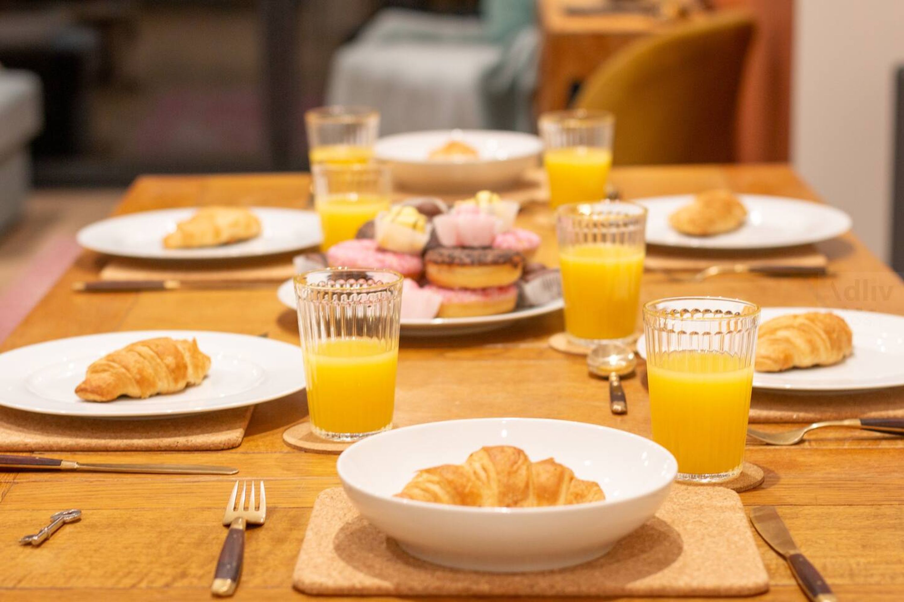 Une table de petit-déjeuner avec des croissants, des pâtisseries et des verres de jus d’orange.