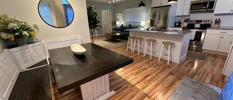 A modern kitchen with a central island, white cabinetry, and a stainless steel refrigerator.