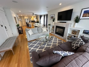 A living room with a sofa, a coffee table, a fireplace, and a television. - 86 Dr Marcus House - Popular Broadway Area (Newport)