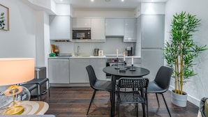 Une cuisine moderne avec des meubles blancs, un four à micro-ondes et un coin repas comprenant une table et des chaises.