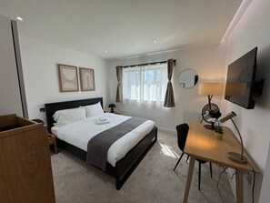 A modern hotel room with a bed, bedside table, desk, and a TV mounted on the wall. - Perfect London Old Brompton Apartment (London)