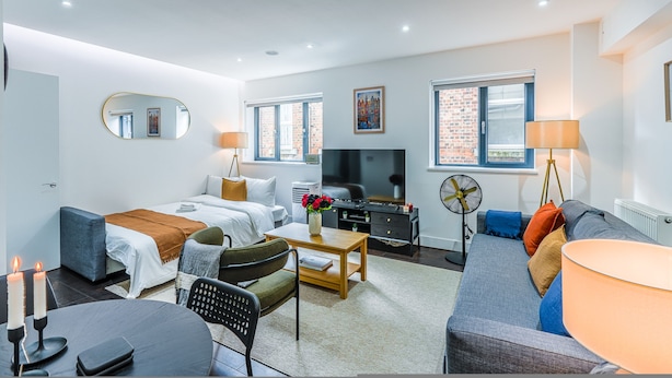Une chambre d’hôtel moderne équipée d’un lit, d’un canapé, d’une télévision et d’un coin repas.