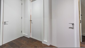 Un couloir avec trois portes blanches, un plancher en bois et un mur blanc.