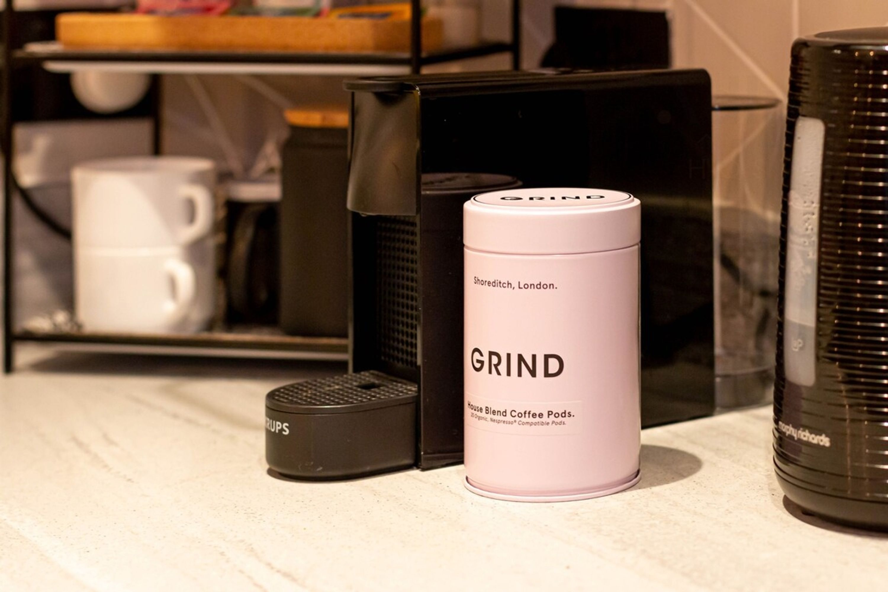 Una cafetera, un contenedor para cápsulas de café y una máquina de café sobre una encimera.