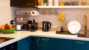 Une cuisine moderne avec des meubles de couleur turquoise, une machine à café, une bouilloire et divers ustensiles de cuisine.