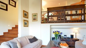 A spacious living area with a sofa, a coffee table with decorative items, and a staircase leading to an upper level. - Villa With Incredible sea Views and Pool Sleeps 7 (Andraitx)