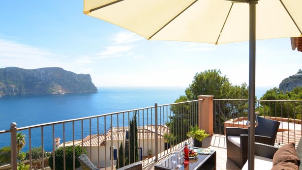 A balcony with outdoor furniture, a table, and a large umbrella. - Villa With Incredible sea Views and Pool Sleeps 7 (Andraitx)