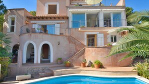 A two-story house with a swimming pool, featuring a balcony with a railing and potted plants. - Villa With Incredible sea Views and Pool Sleeps 7 (Andraitx)