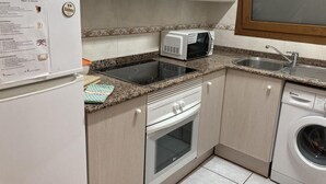 Een kleine keuken met een koelkast, magnetron, fornuis, oven en wasmachine.