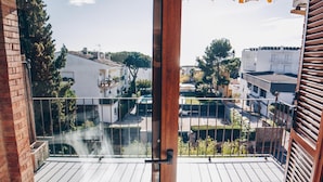 Een balkon met uitzicht op woongebouwen en bomen.