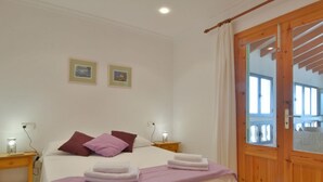 A bedroom with a bed, two nightstands, a wooden door, and two framed pictures on the wall. - Mallorca Beach Front Line Apartment 6 Pers (Santa Margalida)