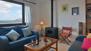 A living room with a sofa, a coffee table, a bookshelf, and a fireplace. - Mallorca Beach Front Line Apartment 6 Pers (Santa Margalida)