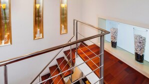 A staircase with a metal railing, wooden steps, and a glass display case with decorative items on the landing. - Victoria City Center 1 Downtown Luxury Duplex (Barcelona)