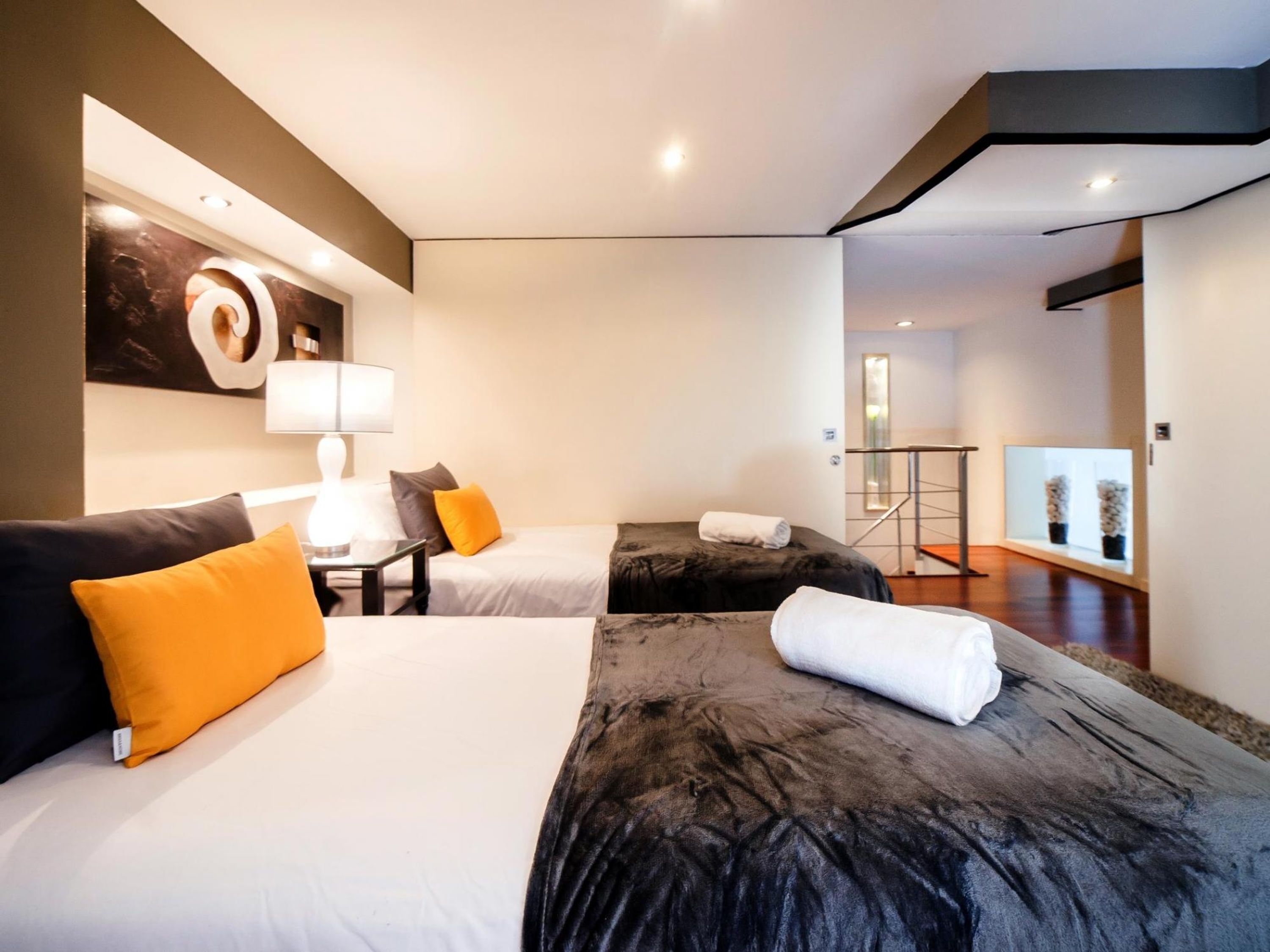 Ein modernes Hotelzimmer mit zwei Betten, einem Schreibtisch und einem großen Spiegel.