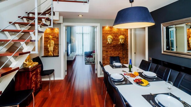 A modern dining area with a long table, chairs, and a staircase. - Victoria City Center 1 Downtown Luxury Duplex (Barcelona)