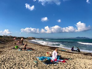 Une plage où des gens se prélassent au soleil et sont assis sur des serviettes.