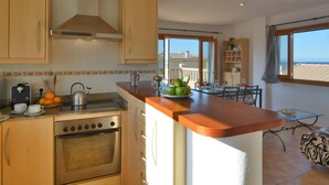 A kitchen with wooden cabinets, a stove, and a dining area with a table and chairs.