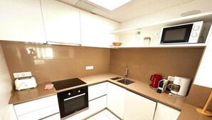 A compact kitchen with a built-in oven, a microwave, a coffee maker, and a toaster. - Charming Apartment in La Fosca Beach (Palamós)