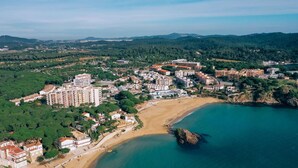 An aerial view of a coastal town with a beach, residential buildings, and a rocky outcrop in the water. - Charming Apartment in La Fosca Beach (Palamós)