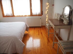 Un dormitorio con una cama, un tocador con espejo y un radiador.