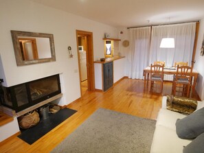 Una sala de estar con chimenea, un comedor con mesa y sillas, y una cocina al fondo.