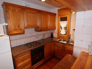 Una cocina con armarios de madera, encimera de granito, estufa, fregadero y refrigerador.