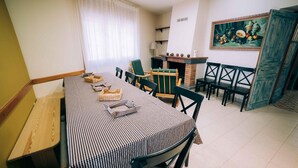 A dining area with a checkered tablecloth, wooden chairs, a brick fireplace, and a painting on the wall. - Casa Rural en el Centro Hist Rico de Gualta (Gualta)
