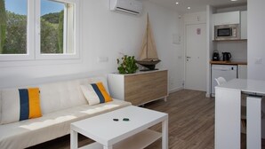 A modern, well-lit room with a white sofa, a small white table, a wooden cabinet, and a sailboat decoration. - Apartament amb Piscina i Parquing Baixos amb Jard (Palafrugell)