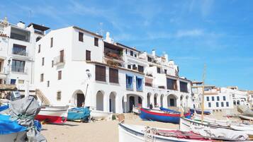 A coastal town with white buildings, a sandy beach, and several boats.