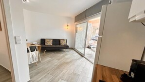 Une cuisine moderne avec un plan de travail en bois, un réfrigérateur noir et une porte-fenêtre coulissante donnant sur un balcon.