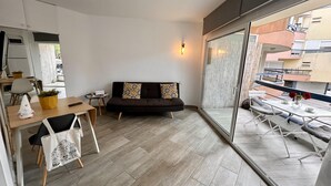 Un salon moderne avec un canapé, une table à manger et un balcon offrant une vue sur la ville.