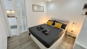 Une chambre à coucher moderne avec un lit, une table de chevet et un miroir au mur.